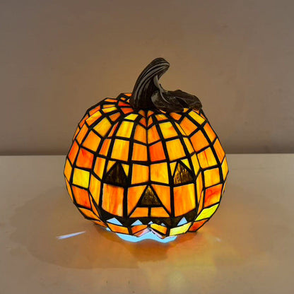 Mosaic jack-o'-lantern lamp seen from slightly above, the lit mosaic running up to a curled dark stem