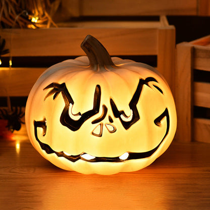 White Scowl carved pumpkin lamp, a cream white pumpkin with a dark-outlined scowling face, lit warm from inside