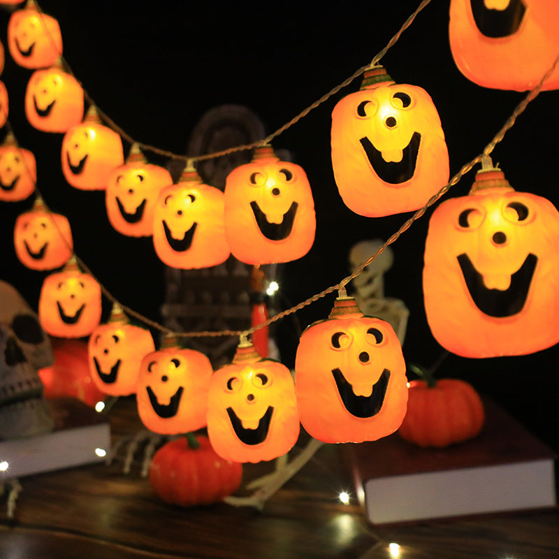 Jack-o'-lantern string lights glowing warm orange in two rows across a dark Halloween table