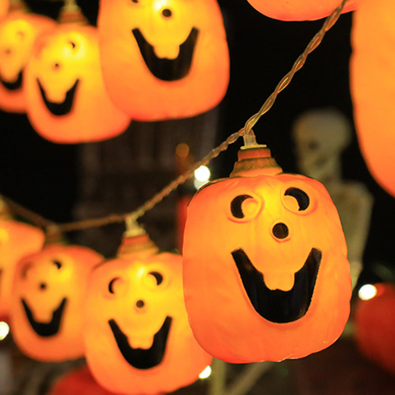 One lit jack-o'-lantern on a string in sharp focus, more glowing faces soft behind it