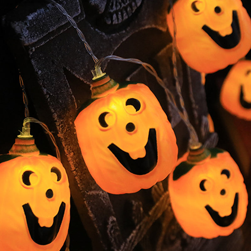 Jack-o'-lantern string lights hanging against a dark carved stone Halloween prop