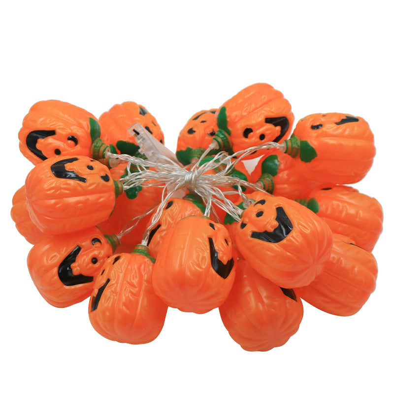 A jack-o'-lantern string light bundled up on white, the orange lanterns tied together with their clear wire