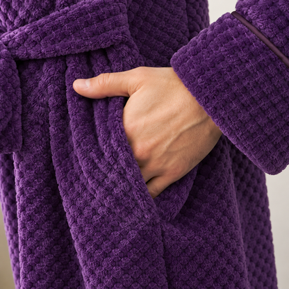 Close-up of a hand in the side pocket of the purple waffle fleece bathrobe, with the piped cuff above