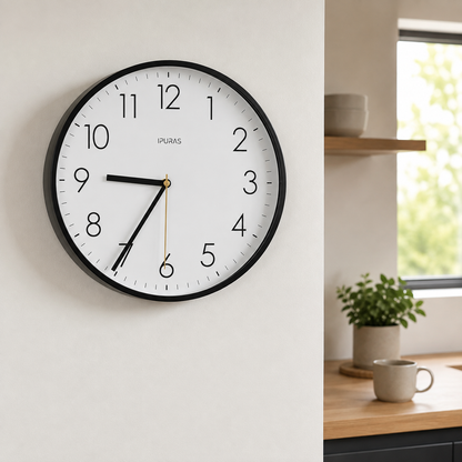 Black wall clock hanging on a kitchen wall in bright morning daylight