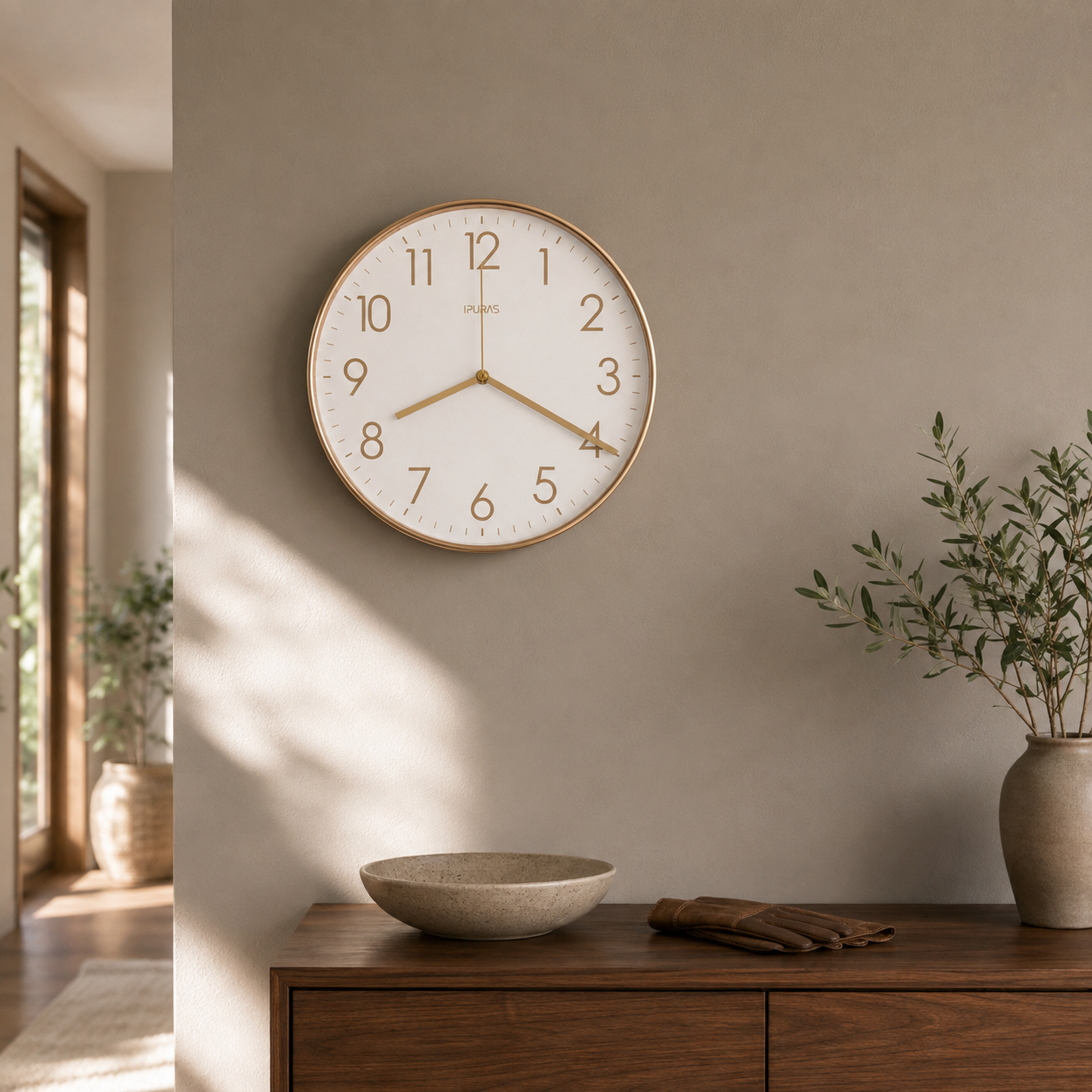 Gold wall clock hanging above a walnut sideboard in a sunlit hallway