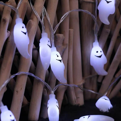 Cool white lit ghost pendants on clear twisted wire draped across a bamboo screen at night