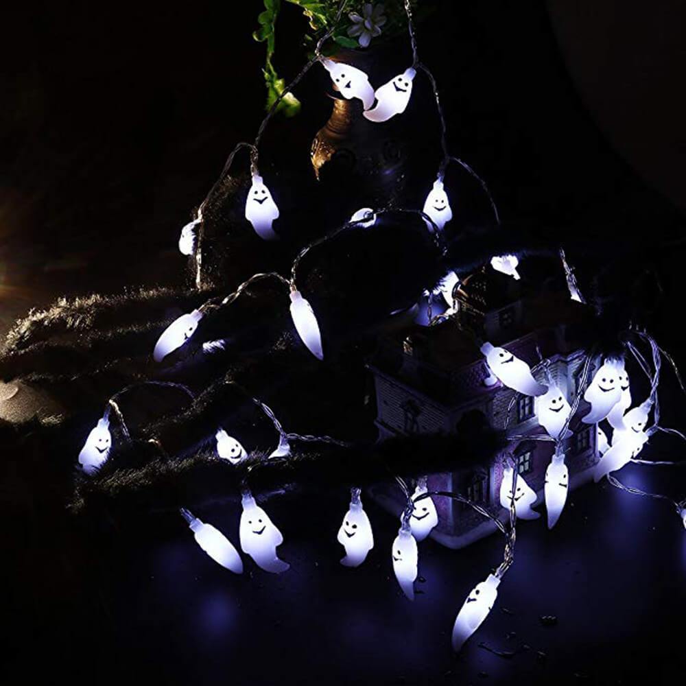 Cool white ghost string lights spread across a dark table beside a model house at night