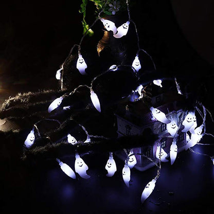 Cool white ghost string lights spread across a dark table beside a model house at night