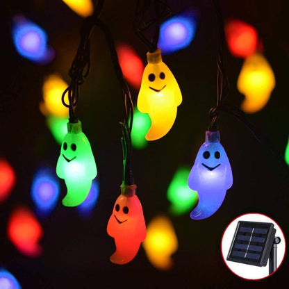 Multicolor ghost string lights on black solar cable glowing red, yellow, green and violet at night
