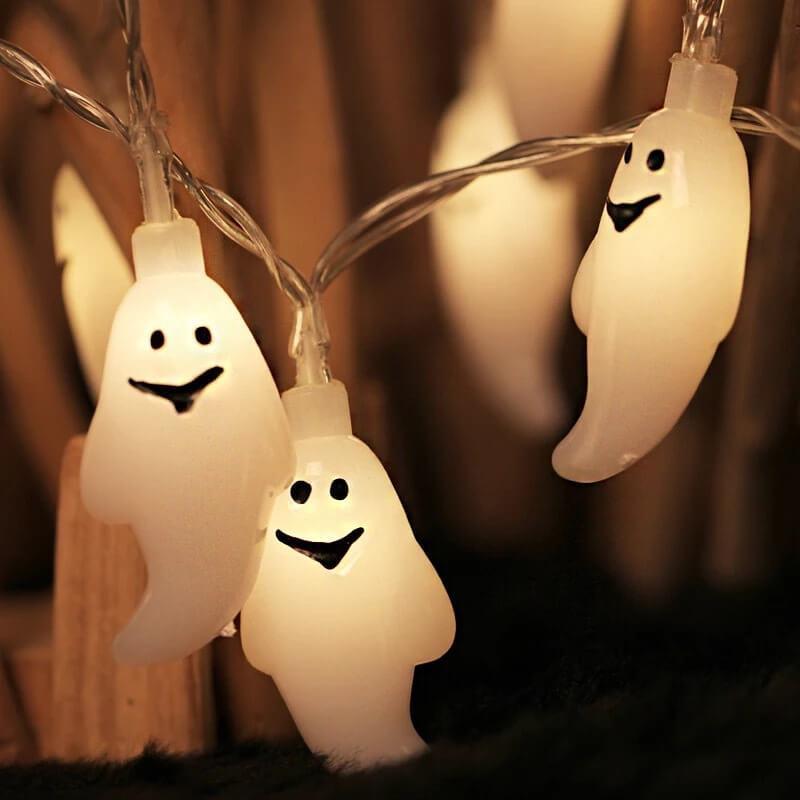Warm white LED ghost string lights glowing on clear wire in front of a wooden fence at night