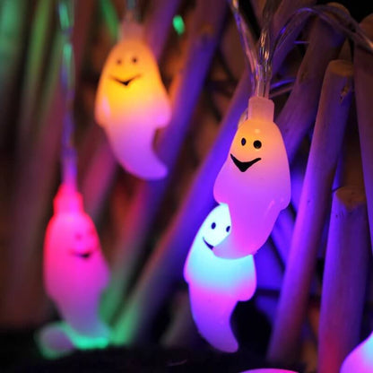 Multicolor LED ghost string lights glowing yellow, pink and teal against a bamboo screen at night