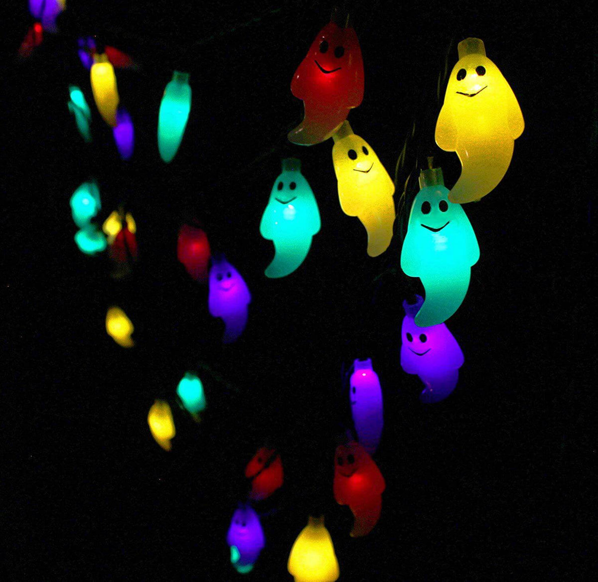Solar ghost string lights on dark green cable glowing red, yellow, teal and violet outdoors at night