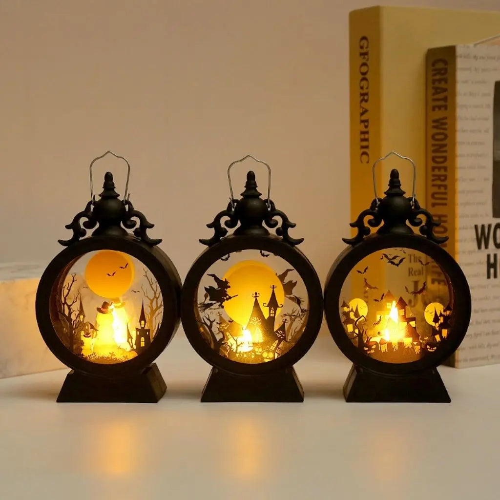 Three Halloween lanterns lit side by side on a table beside a stack of books