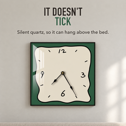 Text image: It doesn't tick. A square wall clock with a beige face and green border above a bed, silent quartz movement
