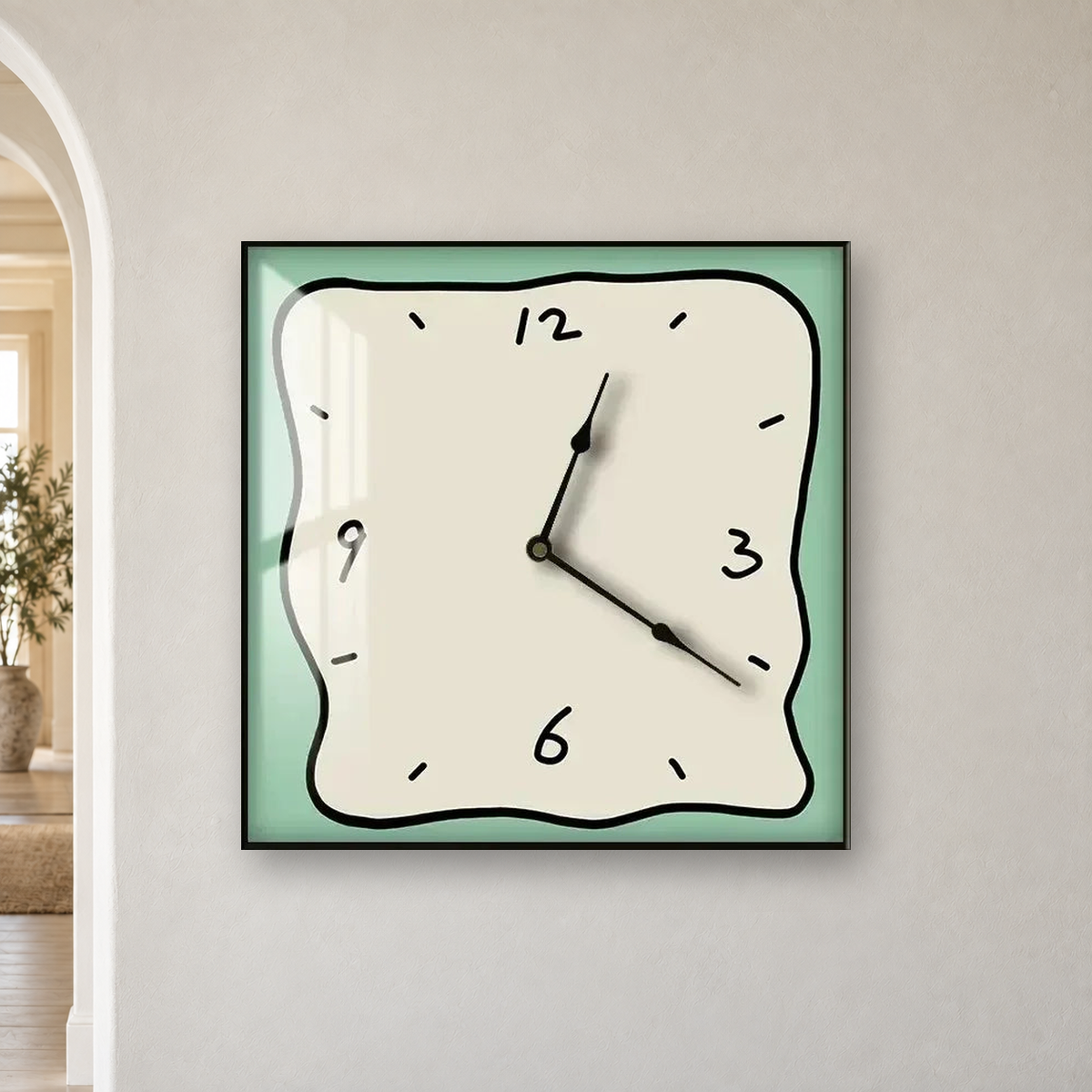 Square wall clock with a wavy doodle-style outline, a beige face and a sage border, hanging centred on an off-white wall beside an arched doorway