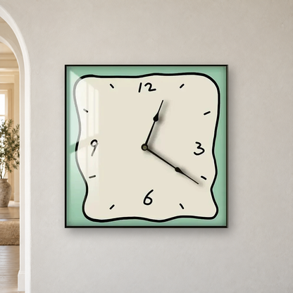 Square wall clock with a wavy doodle-style outline, a beige face and a sage border, hanging centred on an off-white wall beside an arched doorway