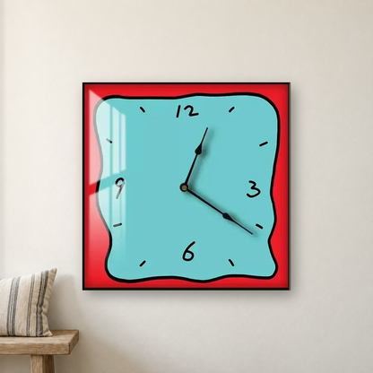 Square wall clock with a wavy doodle-style outline, a blue face and a red border, hanging centred on an off-white wall above a bench