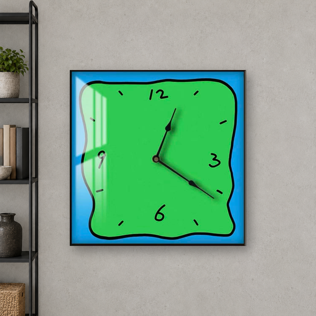 Square wall clock with a wavy doodle-style outline, a green face and a blue border, hanging centred on a grey concrete wall beside a black bookcase