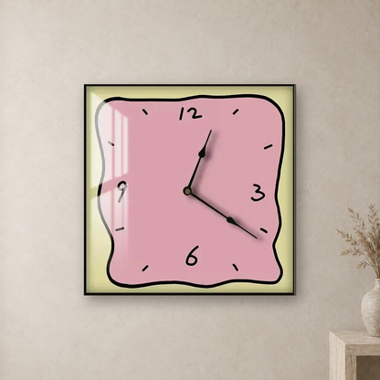 Square wall clock with a wavy doodle-style outline, a pink face and a pale yellow border, hanging centred on a stone plaster wall above a travertine console