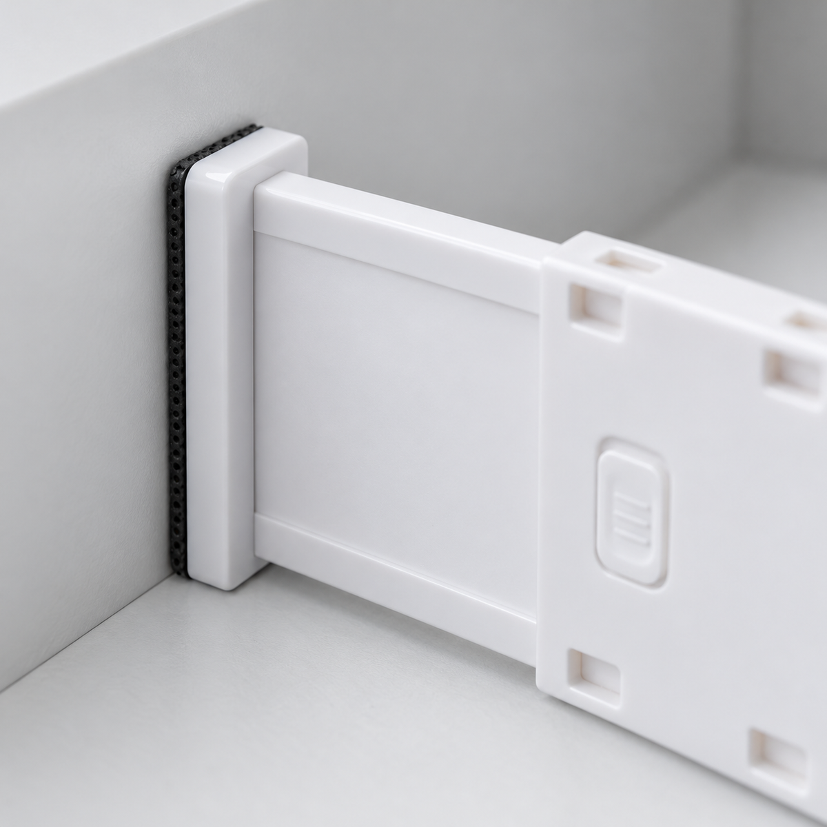 Close-up of a drawer divider end plate with its black dotted pad pressed flat against the drawer wall
