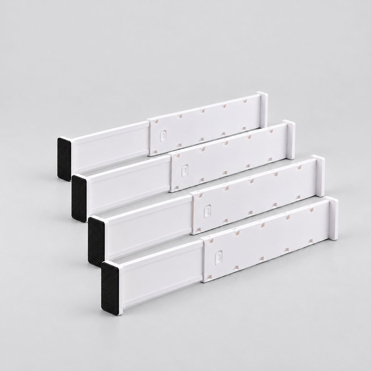 Four long white expandable drawer dividers lined up on a light grey background