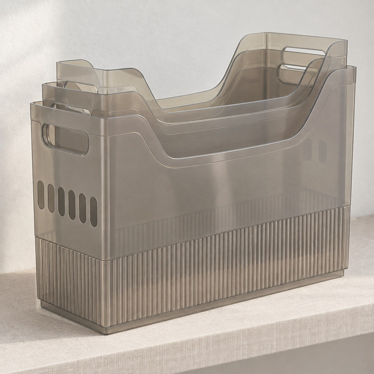 Small, medium and large gray translucent storage bins nested inside one another on a linen-covered shelf