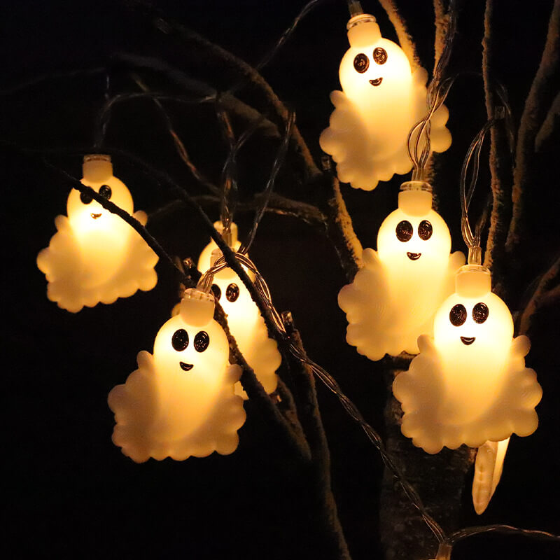 Ghost string lights hanging in a bare tree at night, each small white ghost glowing warm white from inside