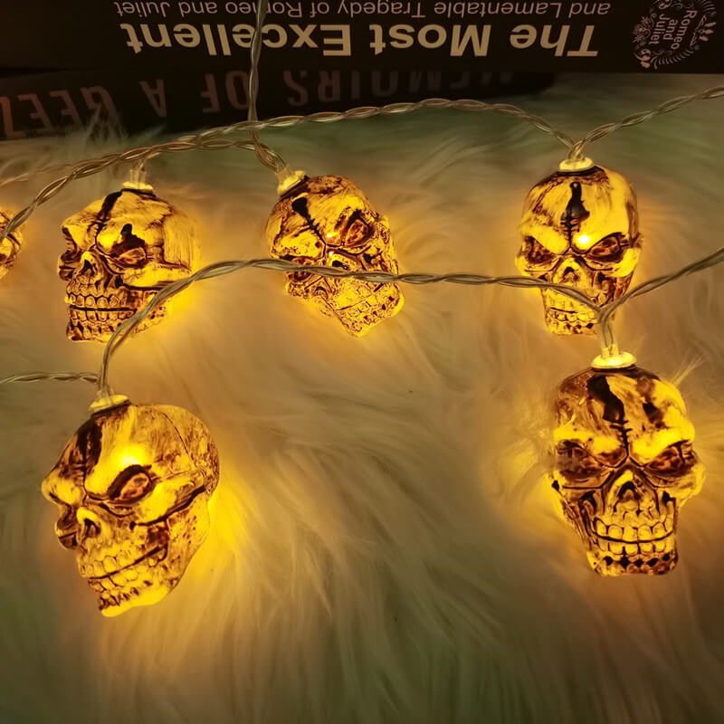 Close view of five lit skull string lights on white fur, the eye sockets, teeth and forehead crack dark against the glow