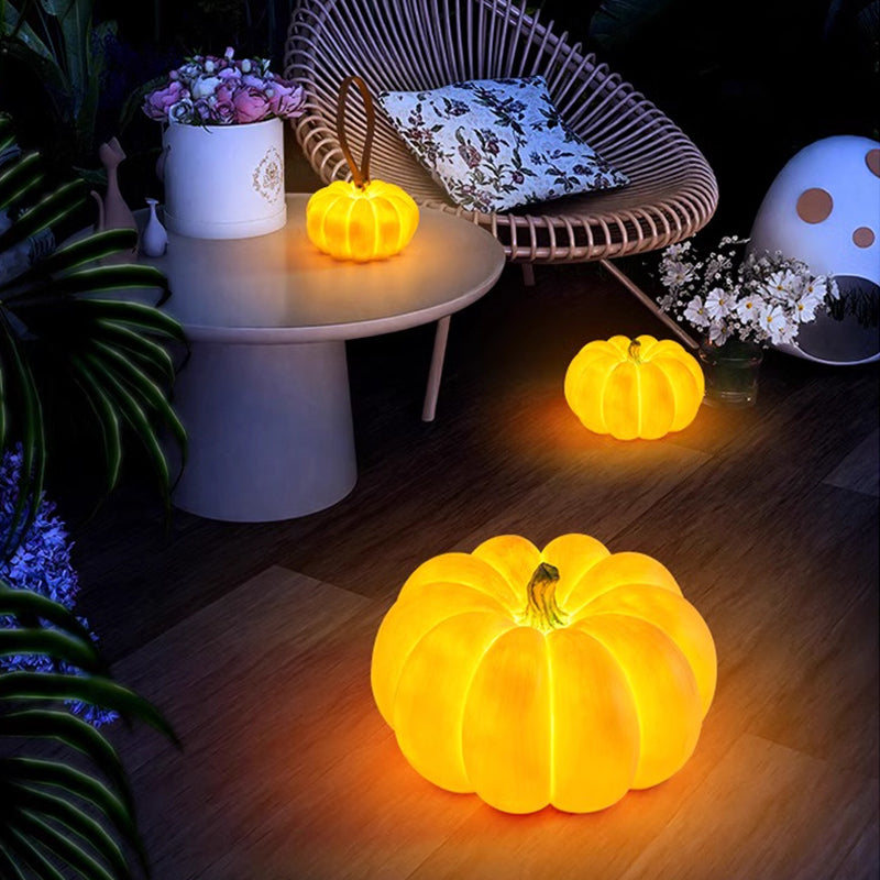 Two glowing pumpkin lamps on a wooden patio floor at night beside a wicker chair and a side table