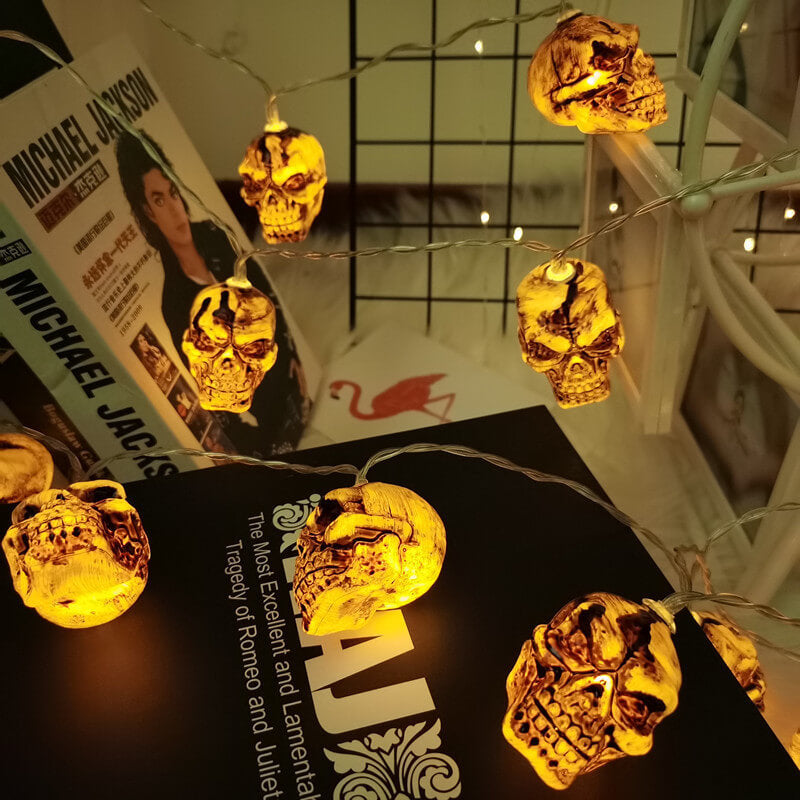 Skull string lights draped over books from above, the clear wire running between the glowing skulls