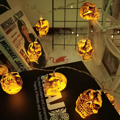 Skull string lights draped over books from above, the clear wire running between the glowing skulls