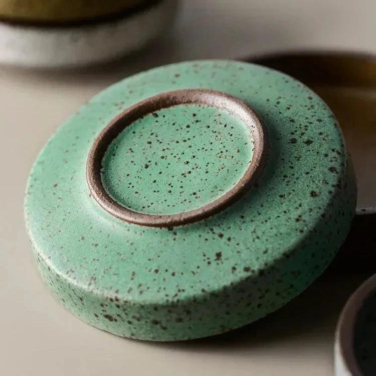 Underside of a green speckled ceramic dish showing its small round foot ring with a brown edge
