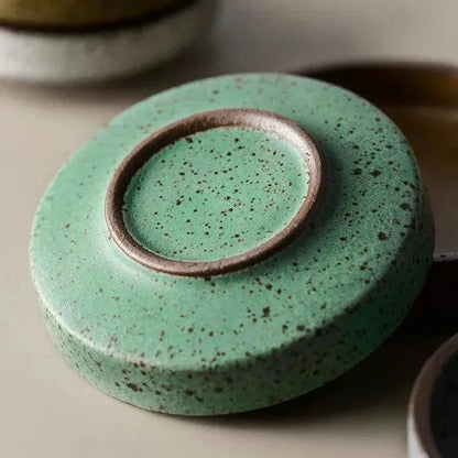Underside of a green speckled ceramic dish showing its small round foot ring with a brown edge