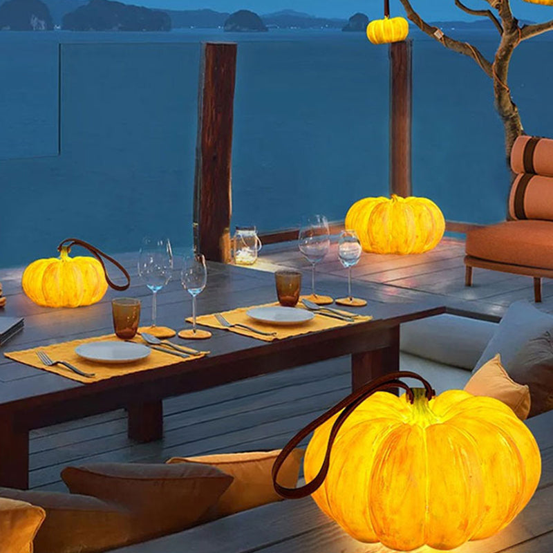 A glowing pumpkin lamp by the railing of a terrace at dusk, next to a table laid for dinner above the sea