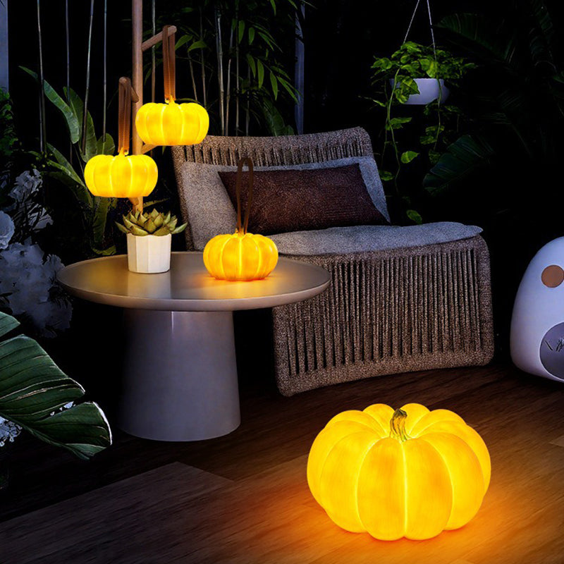 A glowing resin pumpkin lamp on a patio floor at night in front of a woven lounge chair