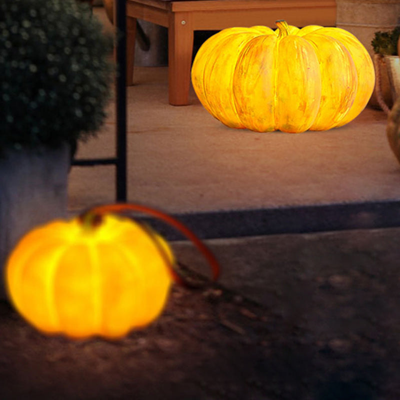A glowing pumpkin lamp on a paved porch at night beside a wooden bench and a potted plant