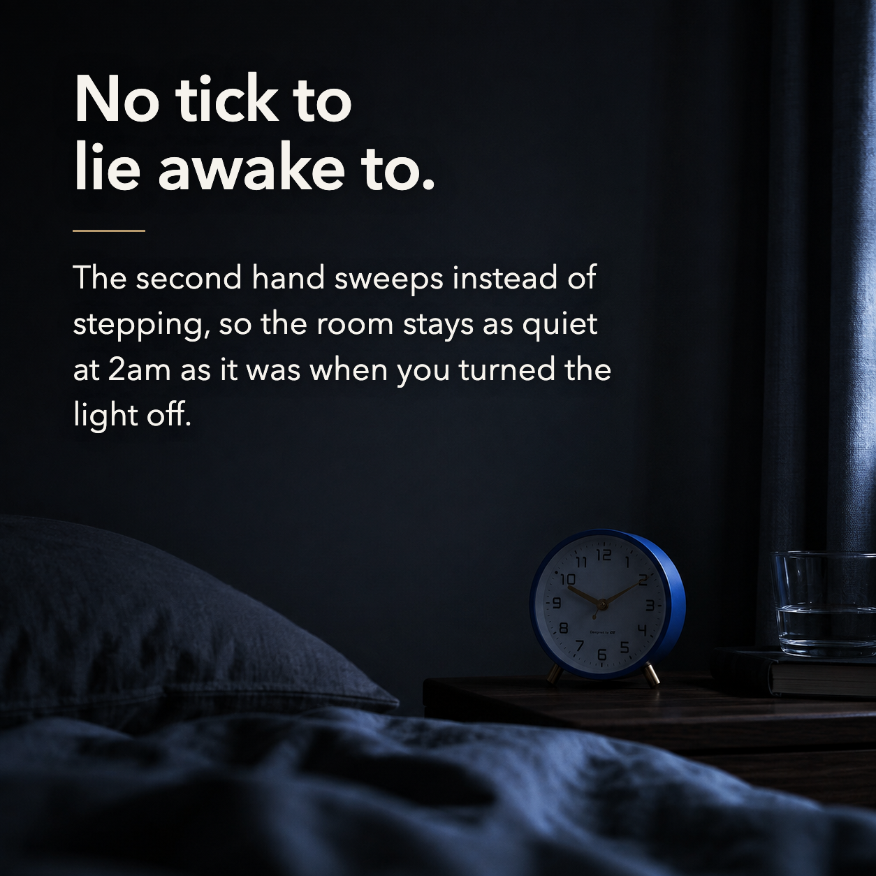 Dark quiet bedroom at night with the navy alarm clock on the nightstand. Text reads: No tick to lie awake to.